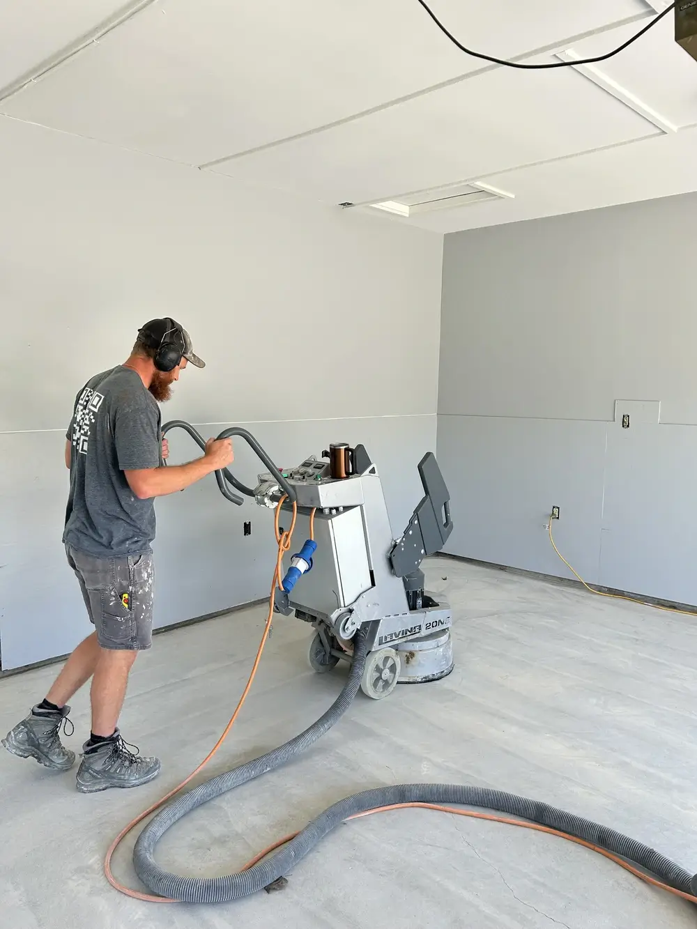 Contractor grinding a concrete garage floor during epoxy floor preparation