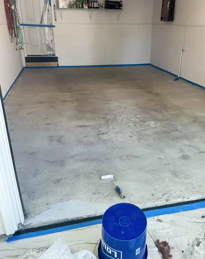Bare concrete garage floor prepared and masked before epoxy coating installation