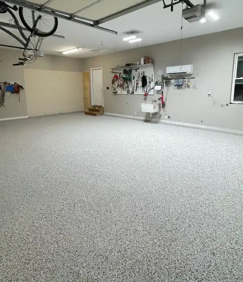Gray epoxy flake garage floor in a residential garage with wall-mounted tools