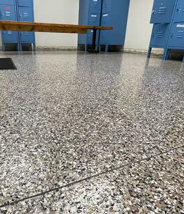Decorative epoxy flake floor in a commercial locker room with blue lockers