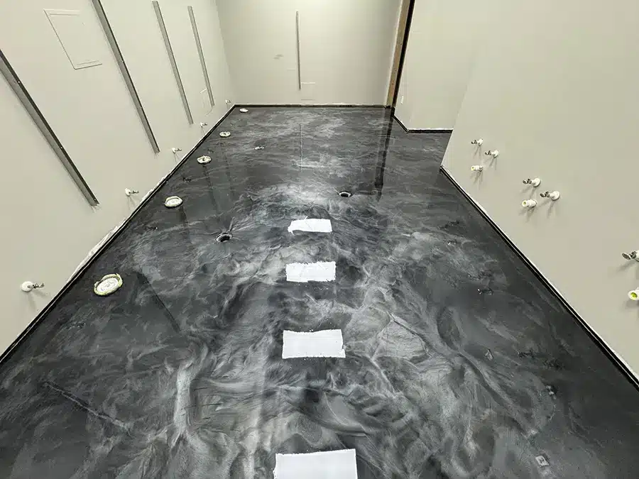 Black metallic epoxy floor with gray marbling in a residential interior under construction