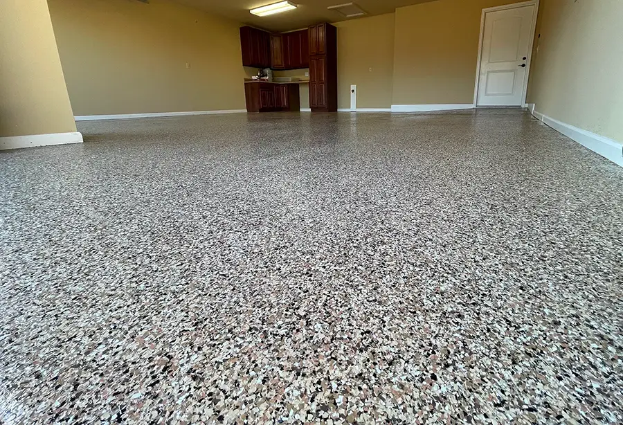Decorative epoxy flake floor with tan, black and white chips in a finished garage