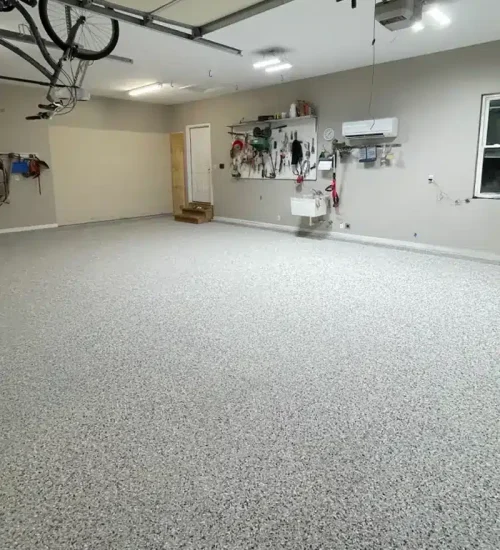 Gray epoxy flake garage floor in a residential garage with wall-mounted tools