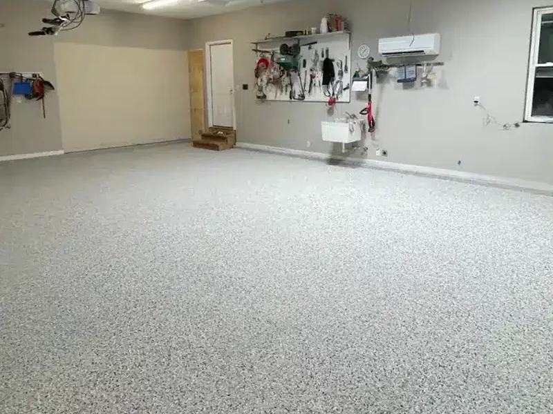 Gray epoxy flake garage floor in a residential garage with wall-mounted tools