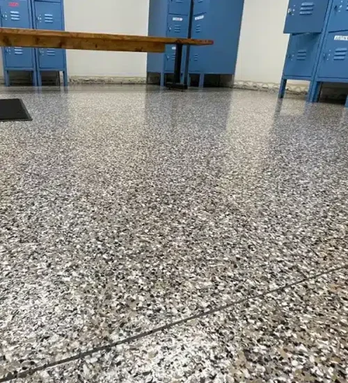 Decorative epoxy flake floor in a commercial locker room with blue lockers