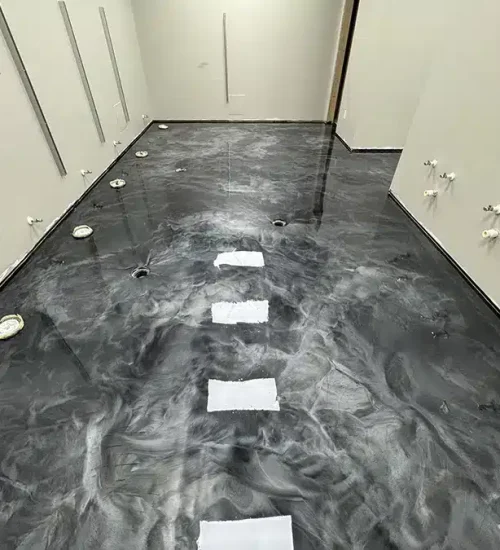 Black metallic epoxy floor with gray marbling in a residential interior under construction