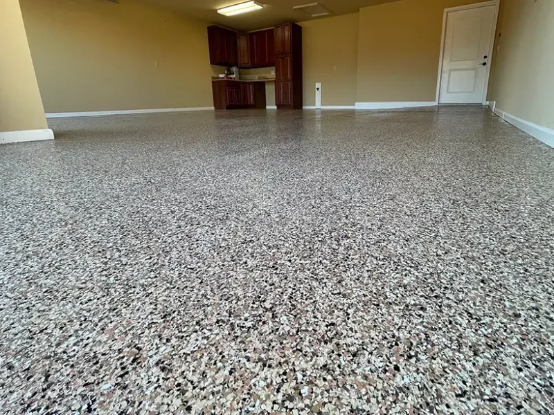Decorative epoxy flake floor with tan, black and white chips in a finished garage